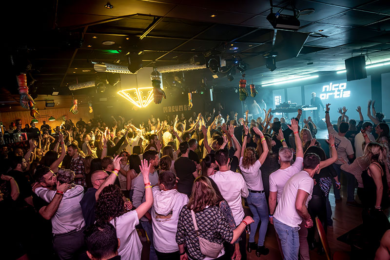 Le public du Lumia Club les mains en l’air, avec Nico Ortiz aux platines au fond de la scène.